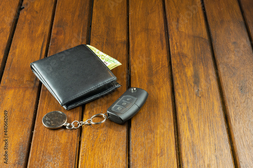 Car key and wallet on wooden background