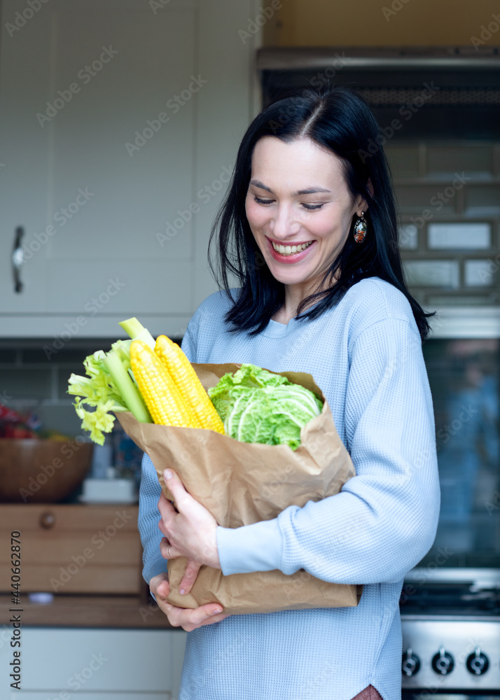 person holding a paper bag with healthy food in kitchen