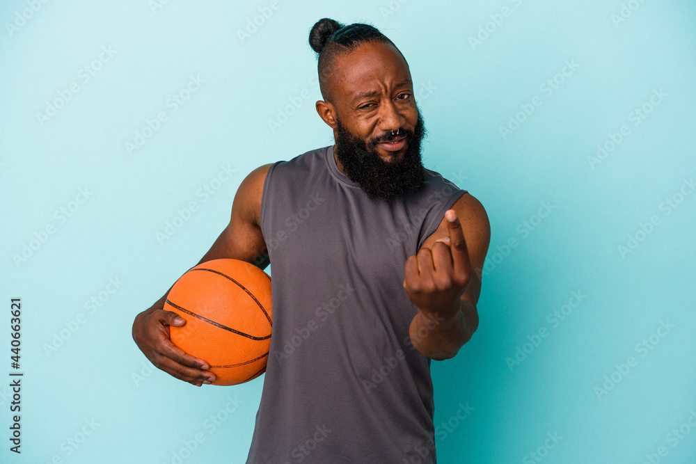 African american man playing basketball isolated on blue background pointing with finger at you as if inviting come closer.