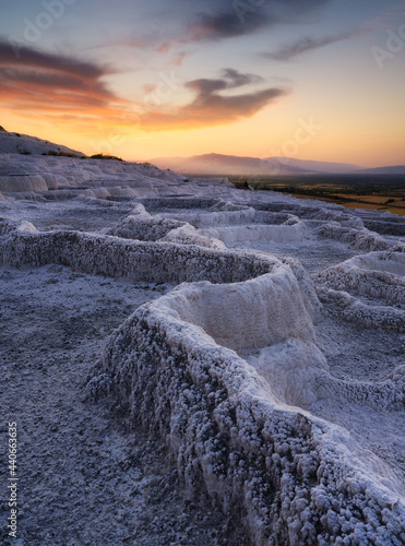 Fototapeta Naklejka Na Ścianę i Meble -  Summer landscape during sunset. The view of the travertines and the bright sunset. Calcium terraces without water. A popular place for tourism. White rocks and sunset. Pamukale, Turkey.