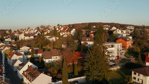 Drone flying above family houses illuminated by bright evening sun. Aerial view on residential zone. Bad Vilbel, Germany. photo