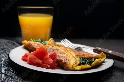Egg omelette with spinach and tomate on dark background. French food