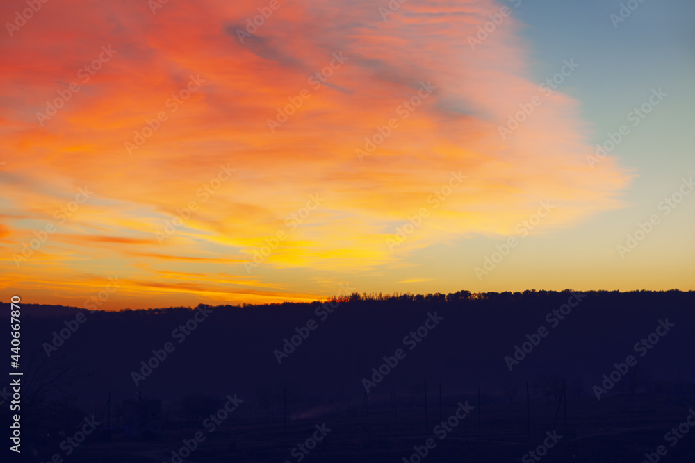 Colorful sunset over the mountain hill . Red beautiful clouds in the evening