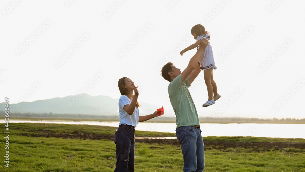 Asian family of father, mother, and two kids having a quality time in meadow. Shot at summer Asian family of father, mother, and two kids having a quality time in meadow. Shot at summer