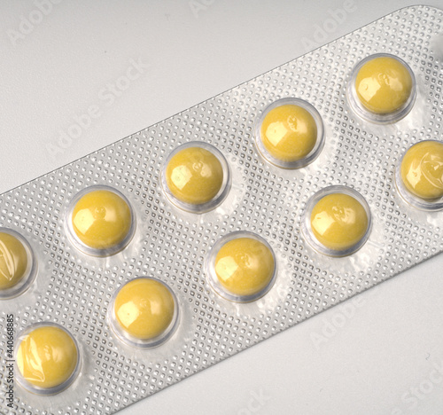 Yellow round tablets in a blister on a white background closeup.