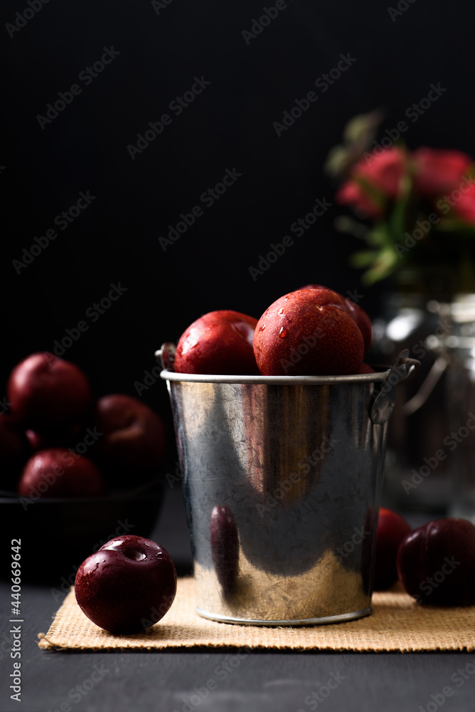 Japanese or Chinese red plum fruit in a bucket on black background Japanese or Chinese red plum fruit in a bucket on black background