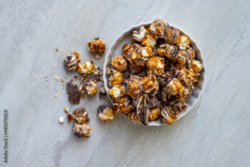 Chocolate caramel popcorn in white dish on light neutral background.