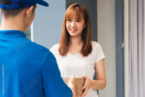 Fotografie Asian young delivery man courier in uniform hold parcel post boxes service shipm