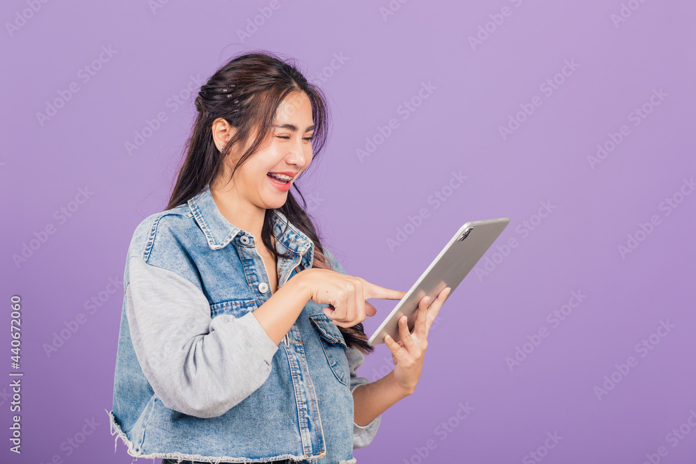 Portrait of Asian beautiful young woman smiling using tablet computer, Happy lifestyle female teen touching screen on digital tablet pc, studio shot isolated on purple background Portrait of Asian beautiful young woman smiling using tablet computer, Happy lifestyle female teen touching screen on digital tablet pc, studio shot isolated on purple background
