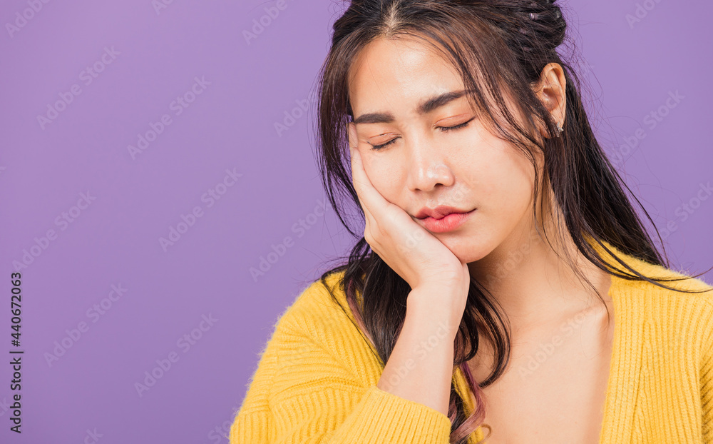 Portrait of Asian beautiful young woman suffering from toothache, female terrible strong teeth pain problem pressing hand to chin, studio shot isolated on purple background, Dental health care concept Portrait of Asian beautiful young woman suffering from toothache, female terrible strong teeth pain problem pressing hand to chin, studio shot isolated on purple background, Dental health care concept