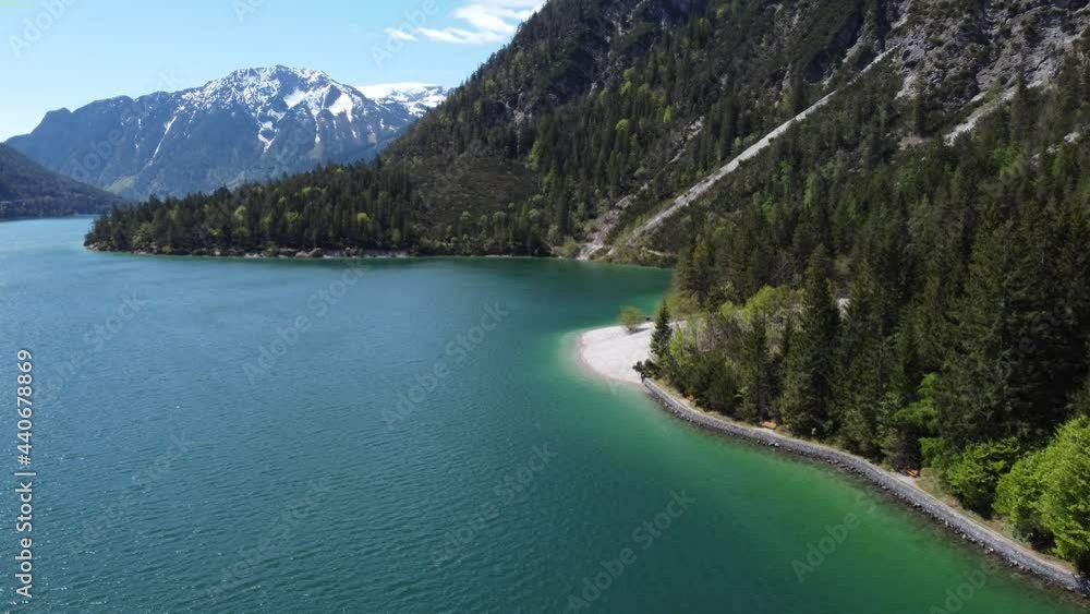 Hiking trail alongside the beautiful lake Achen. Beautiful mountains around and peaks covered with snow. Drone, aerial view of alpine nature. Hiking trail alongside the beautiful lake Achen. Beautiful mountains around and peaks covered with snow. Drone, aerial view of alpine nature.