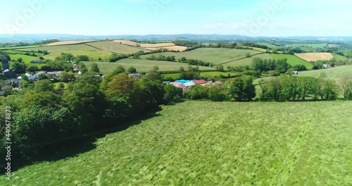 Flying over a field to reveal a working farm and rolling hills in Devon, England photo