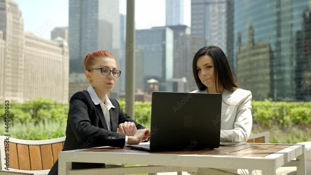 Close-up portrait of two beautiful concentrated business women talking at the table in outdoor restaurant. Close-up portrait of two beautiful concentrated business women talking at the table in outdoor restaurant.