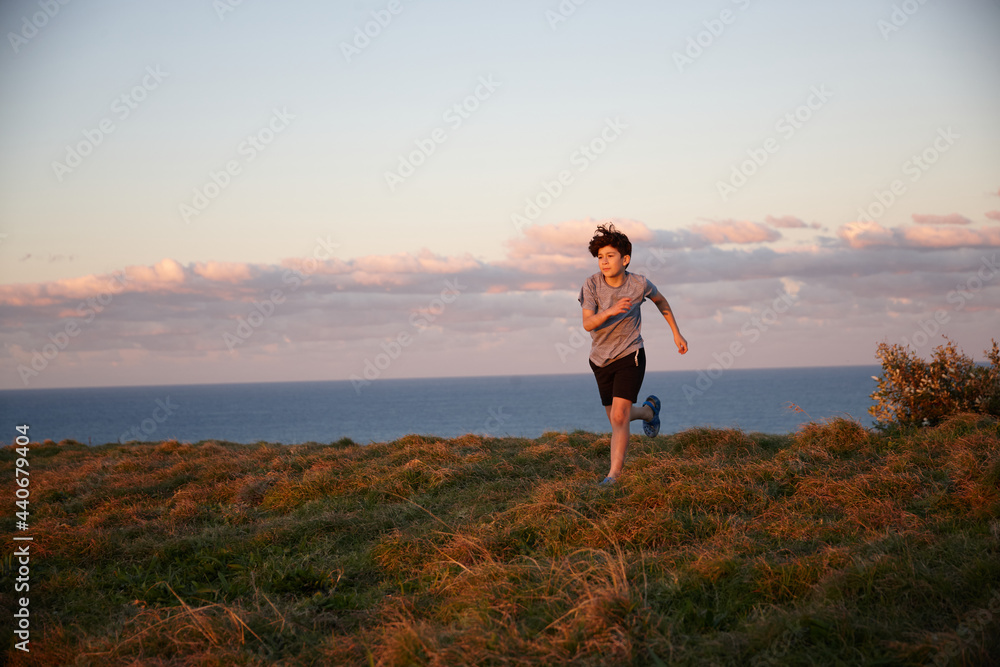 Young boy playing at headland on sunset Young boy playing at headland on sunset