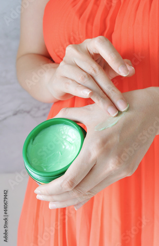 Woman holding a avocado moisturizer bottle and trying it on her hand.