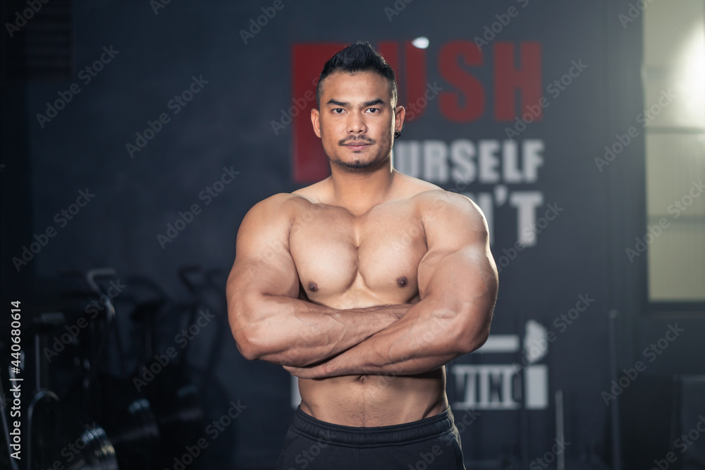 Asian Fitness sportman bodybuilder crossed arm, look at camera in gym.