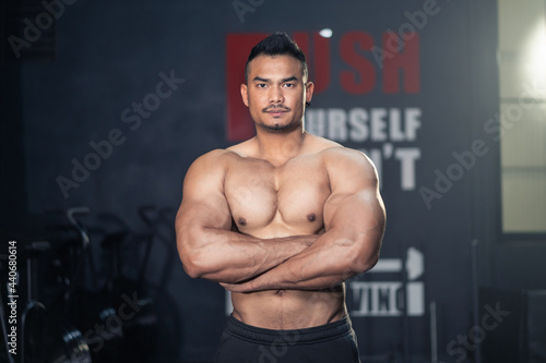 Asian Fitness sportman bodybuilder crossed arm, look at camera in gym.