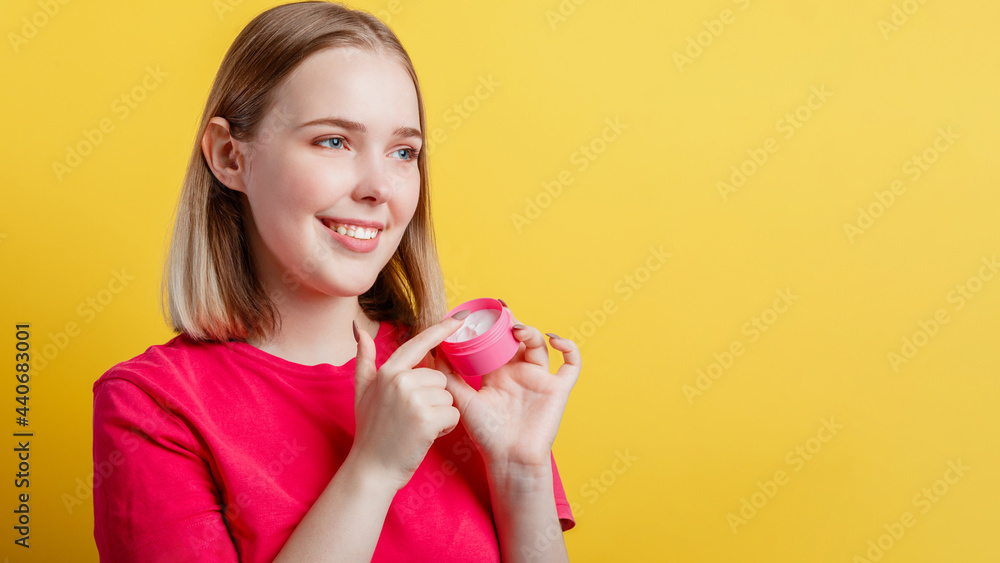 Happy Smiling Woman Portrait applying moisturizing cream hand cream look side on copy space. Teenager girl using skincare cosmetic product isolated over yellow color background Long web banner Happy Smiling Woman Portrait applying moisturizing cream hand cream look side on copy space. Teenager girl using skincare cosmetic product isolated over yellow color background Long web banner