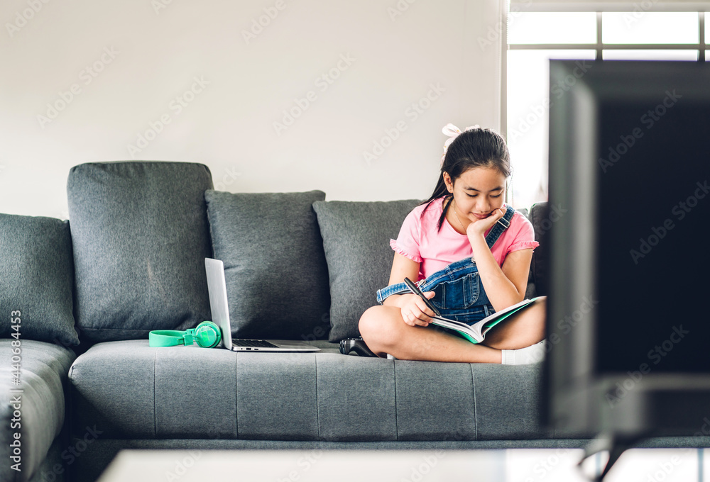 School kid little girl learning and writing in notebook with pencil making homework at home.Education concept School kid little girl learning and writing in notebook with pencil making homework at home.Education concept