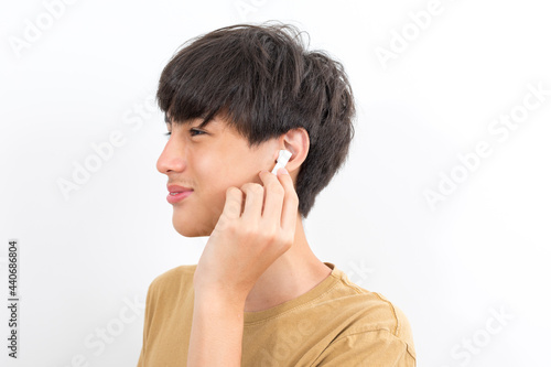 joyful handsome boy teen wearing earpods smiling on white background.