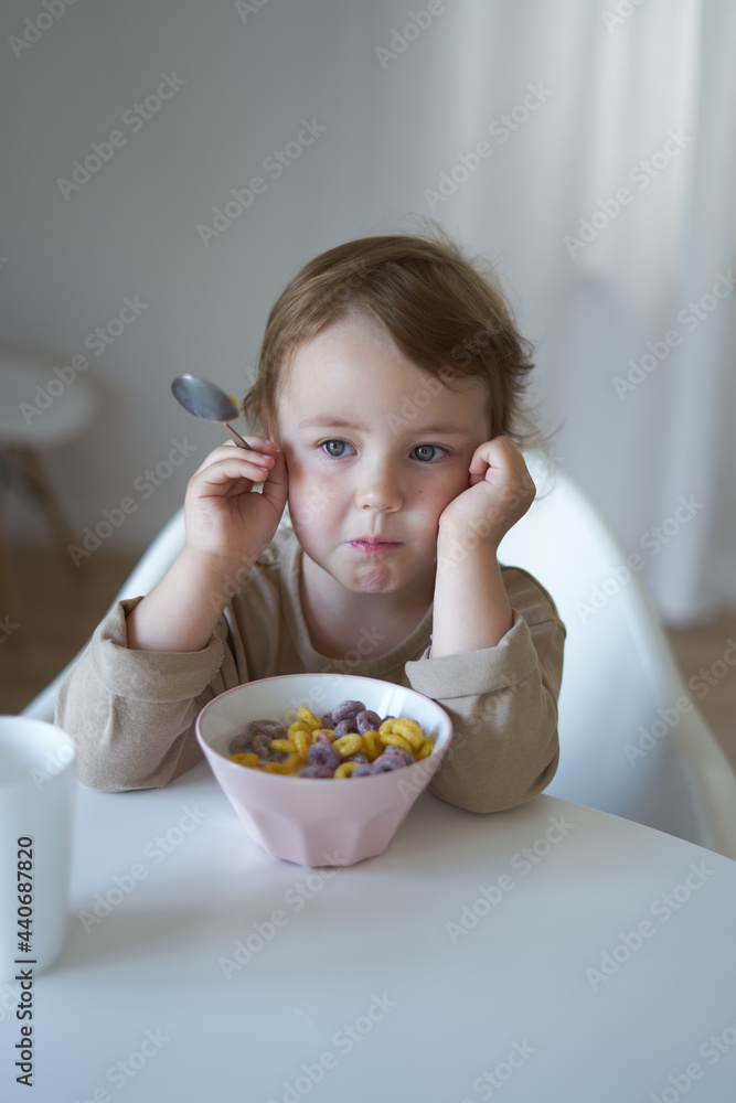 small child girl in the morning breakfast in the house at a white round table small child girl in the morning breakfast in the house at a white round table