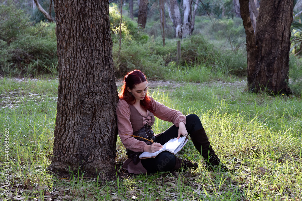 portrait of red haired girl wearing fantasy medieval clothes of a wandering adventurer. natural light in a woodland forest setting. portrait of red haired girl wearing fantasy medieval clothes of a wandering adventurer. natural light in a woodland forest setting.