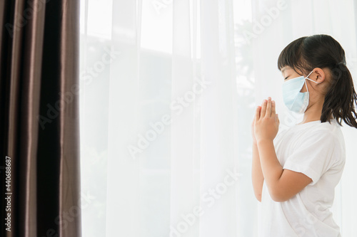Asian kid girl praying wearing mask for protect pm2.5 and Covid-19 Little girl hand praying for thank god.