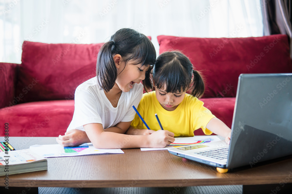 Two asian child girl students study online with teacher by video call together. Siblings are homeschooling with computer laptop during quarantine due to Covid 19 pandemic. Two asian child girl students study online with teacher by video call together. Siblings are homeschooling with computer laptop during quarantine due to Covid 19 pandemic.