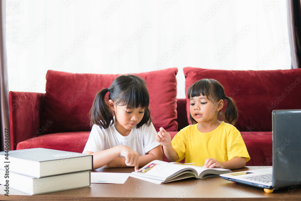 Two asian child girl students study online with teacher by video call together. Siblings are homeschooling with computer laptop during quarantine due to Covid 19 pandemic. Two asian child girl students study online with teacher by video call together. Siblings are homeschooling with computer laptop during quarantine due to Covid 19 pandemic.