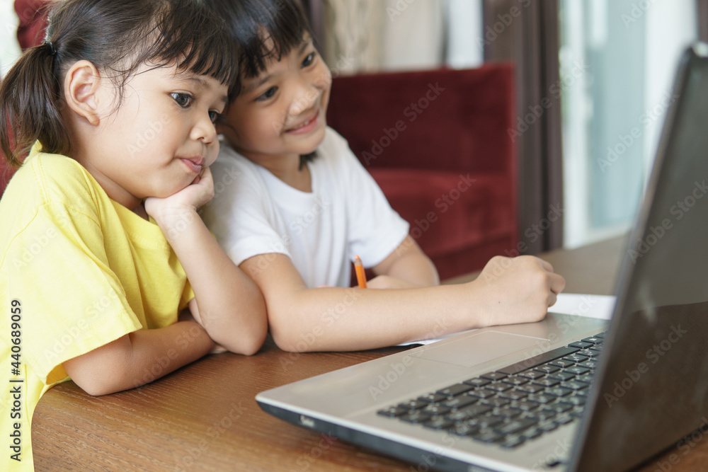 Two asian child girl students study online with teacher by video call together. Siblings are homeschooling with computer laptop during quarantine due to Covid 19 pandemic. Two asian child girl students study online with teacher by video call together. Siblings are homeschooling with computer laptop during quarantine due to Covid 19 pandemic.