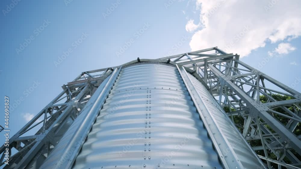 Metal silos on the field. Large containers for storing and processing grains. Silver grain elevators in farmland. Storage tank view from above. Silo with grain. Metal silos on the field. Large containers for storing and processing grains. Silver grain elevators in farmland. Storage tank view from above. Silo with grain.