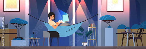 overworked businesswoman freelancer looking at computer screen girl lying in hammock dark night home room interior