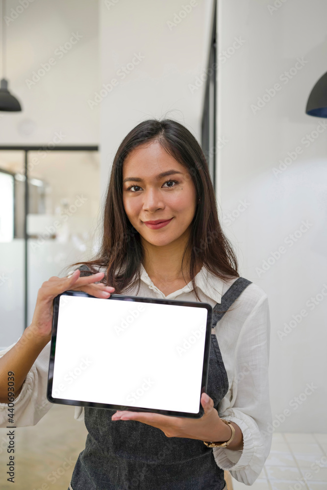 Cheerful young female owner showing digital tablet while standing in coffee shop. Cheerful young female owner showing digital tablet while standing in coffee shop.