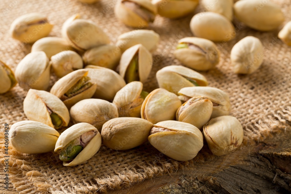Heap of salted, roasted green pistachio nuts snack on burlap sack background, healthy food snack Heap of salted, roasted green pistachio nuts snack on burlap sack background, healthy food snack