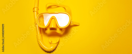 Panoramic photo of yellow diving mask with snorkel, on yellow background with copy space.