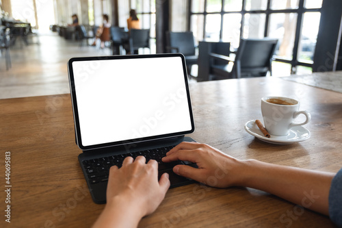 Mockup image of a woman using and typing on digital tablet with blank white desktop screen in cafe
