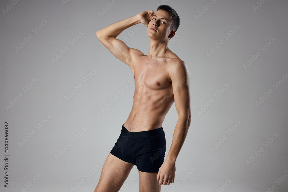 sport guy with a pumped-up torso holds his hands near his face on a gray background cropped view sport guy with a pumped-up torso holds his hands near his face on a gray background cropped view