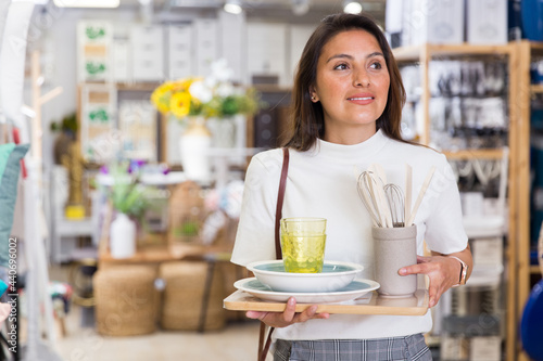Portrait of stylish woman walking in household goods store with purchased