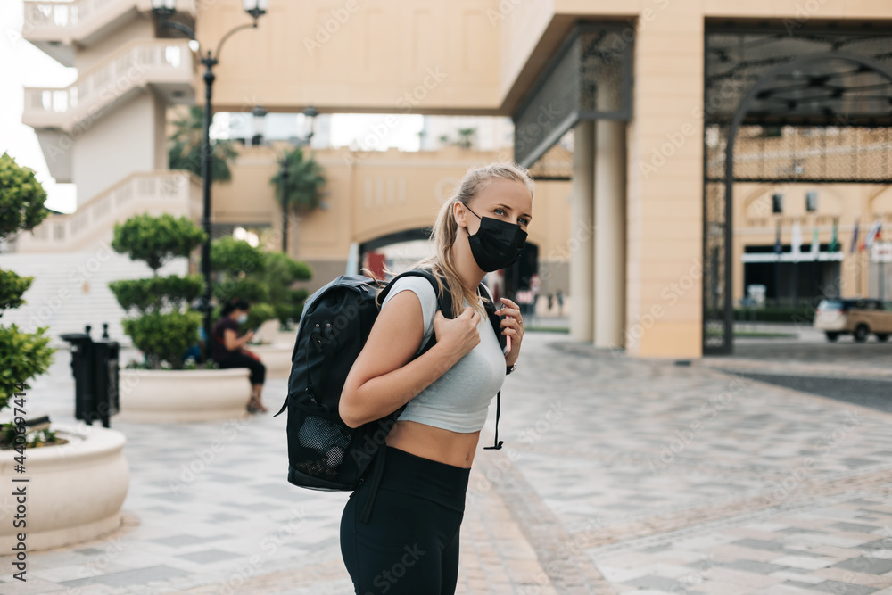 A young tourist girl in a face mask with a backpack is traveling during a vacation. Travel and tourism industry during the pandemic A young tourist girl in a face mask with a backpack is traveling during a vacation. Travel and tourism industry during the pandemic