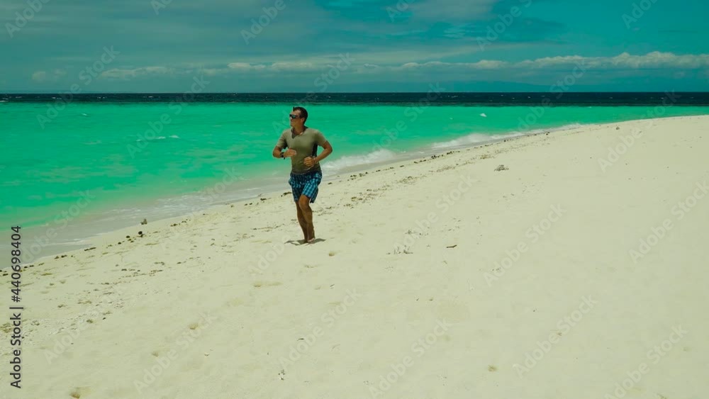 Man jogging on tropical sandy beach near sea. Summer and travel vacation concept. Man jogging on tropical sandy beach near sea. Summer and travel vacation concept.