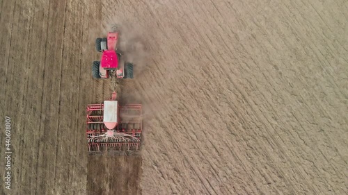 Aerial view a powerful energy-rich tractor pulls a combined tillage unit during the sowing campaign in the spring. Heavy agricultural machinery compacts the soil and dusts. Agribusiness concept photo