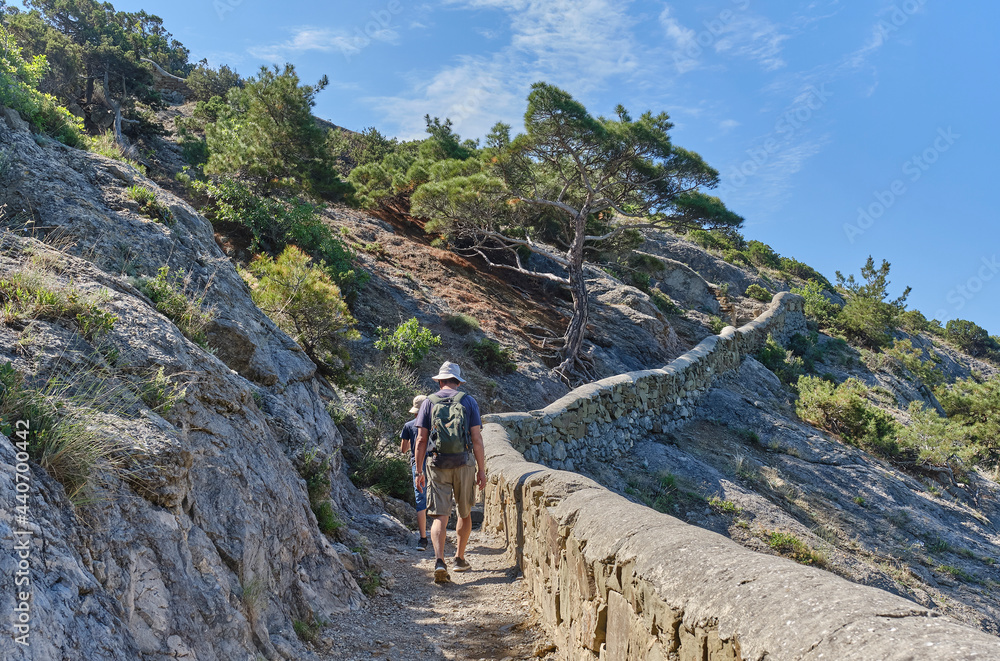 A boy and his grandfather walking on the scenic Golitsyn trail. National botanical reserve New World, Crimea.