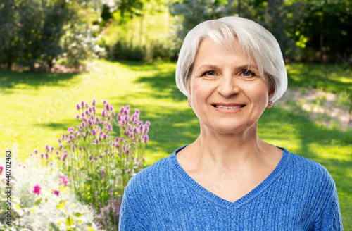 old people and gardening concept - portrait of smiling senior woman in blue sweater over summer garden background