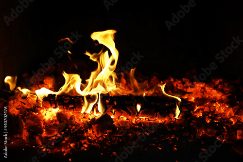 Burning red hot sparks fly from big fire. Burning coals, flaming particles flying off against black background.