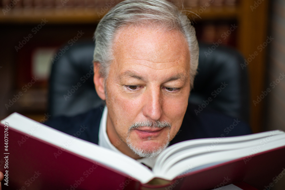 Smiling businessman reading a book in his office Smiling businessman reading a book in his office