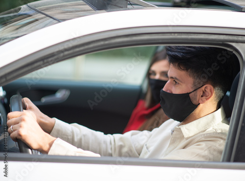 Masked couple in their car, covid coronavirus concept © Minerva Studio
