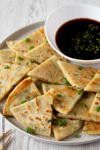 Homemade Scallion Pancakes with Soy Dipping Sauce on a white wooden background, side view.