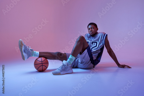 Basketball player poses with ball in studio