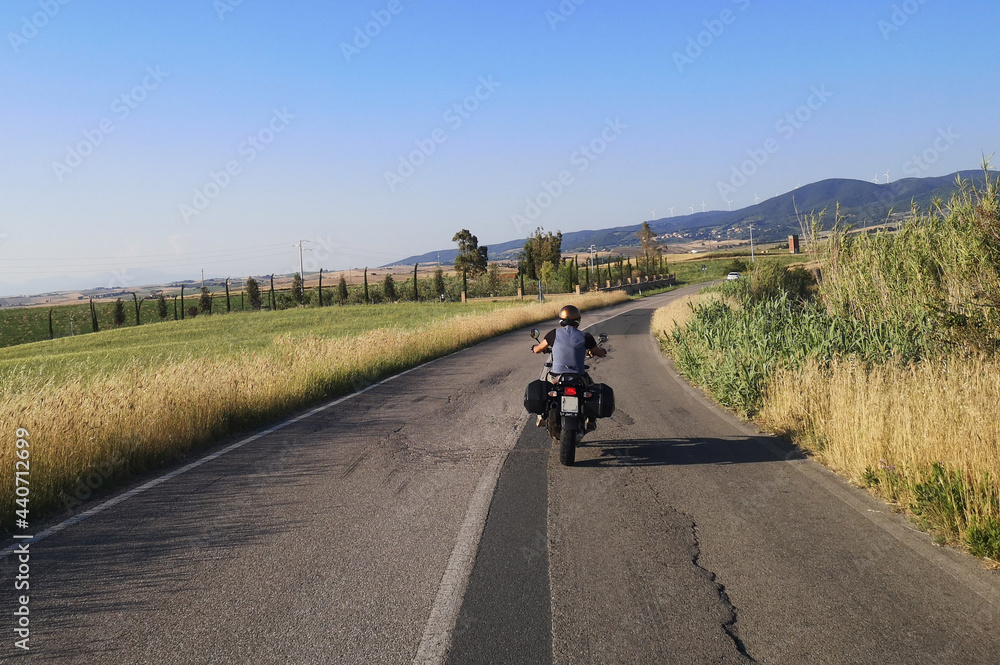 Fototapeta premium motociclista su strada di campagna guida la sua moto da turismo