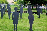 black figures of missing children made of plywood on a green lawn as an installation from a search party in a city park in the summer in Russia
